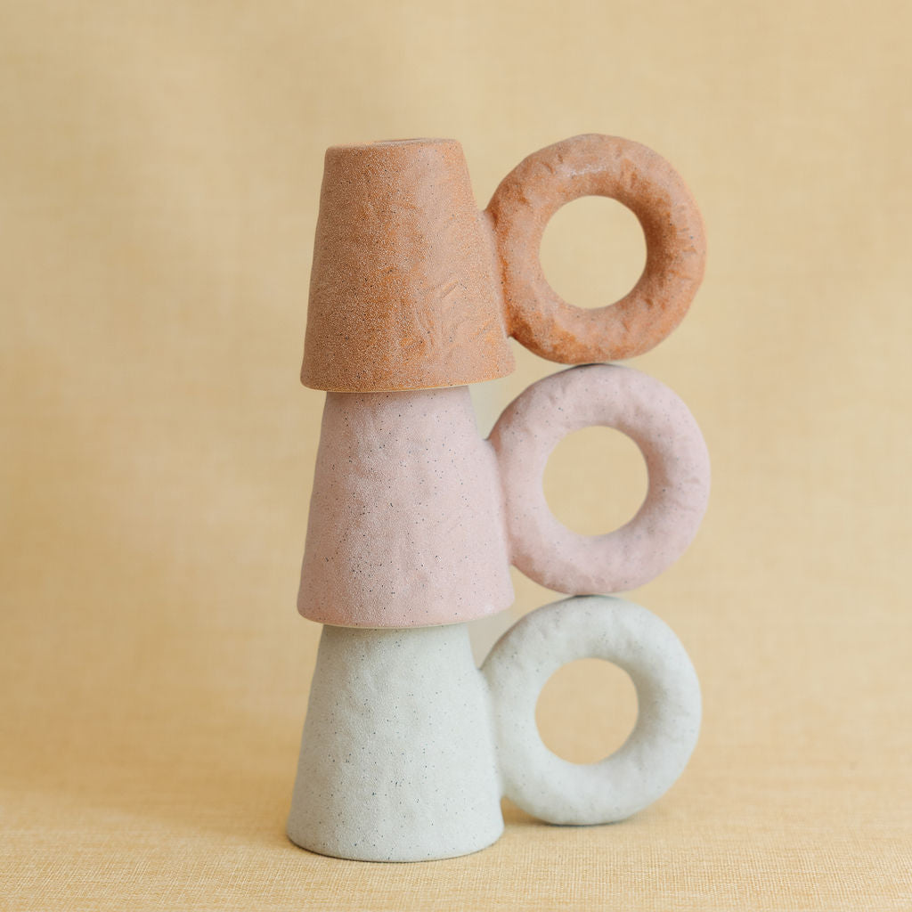 Stack of colorful ceramic candleholders  on a beige background