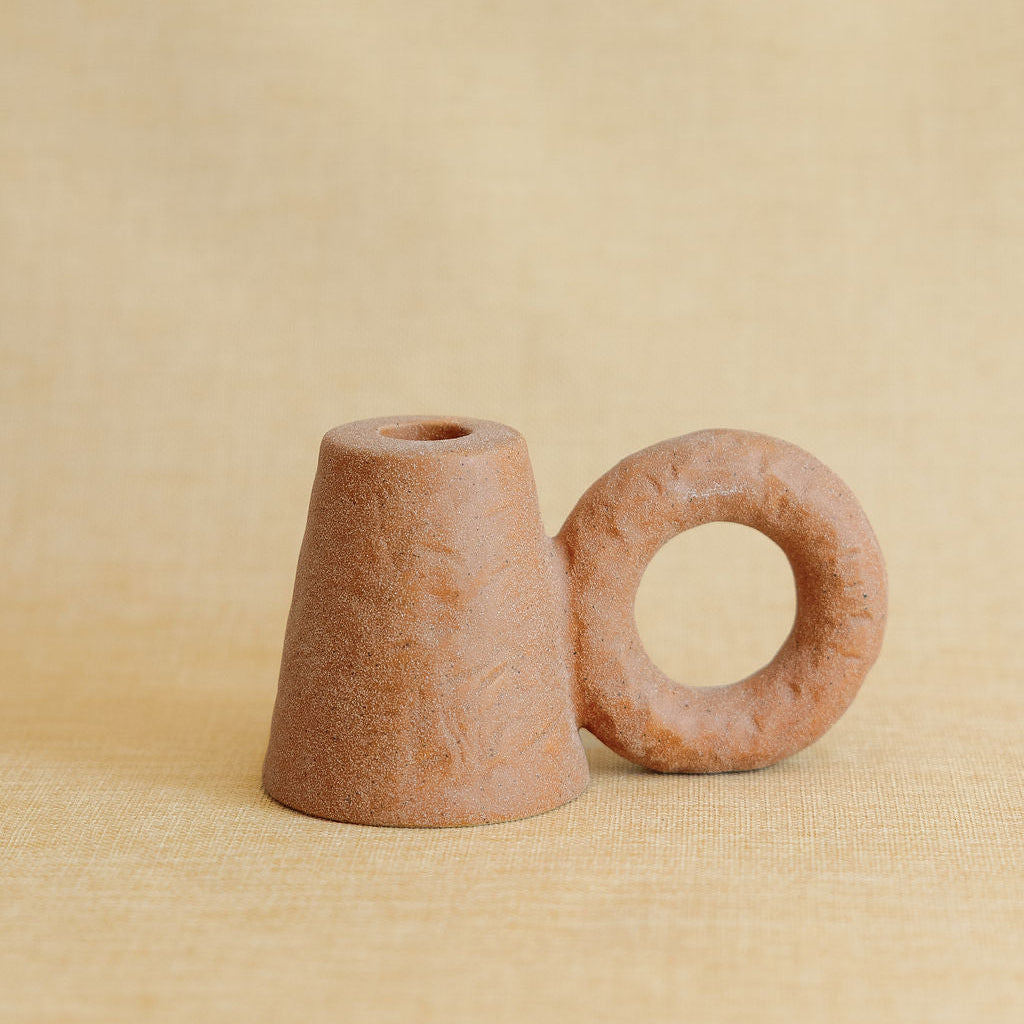 Two terracotta candle holders on a beige background