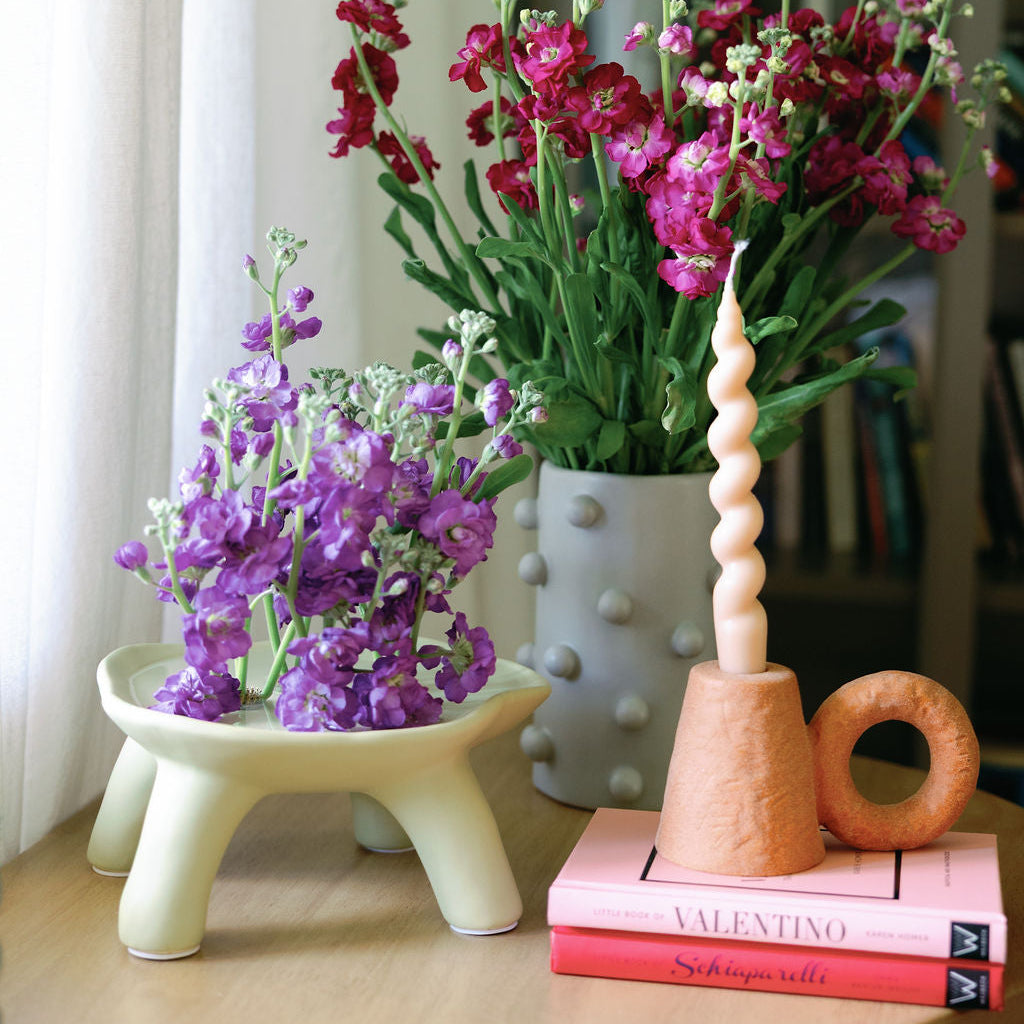 Terracotta textured ceramic candle holder with twist taper candle styled by purple stock flowers.