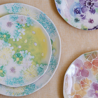 Watercolor wildflower salad plates in purple, teal, green and peach florals styled on linen with a stacked pair.