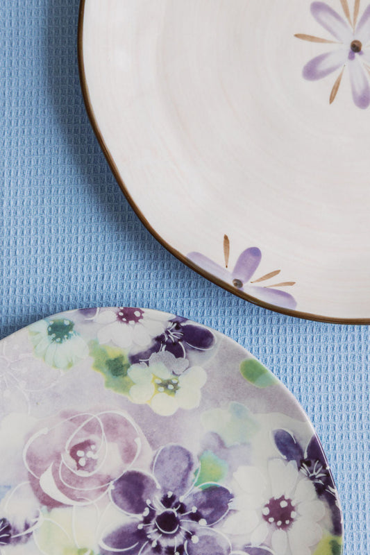 Two ceramic plates with floral designs on a blue textured surface