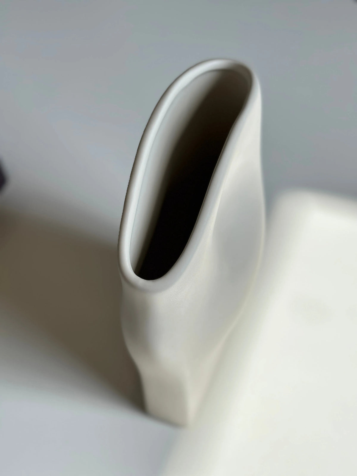 Wave ceramic vase top-down close-up of the angled oval mouth and folded cream surface